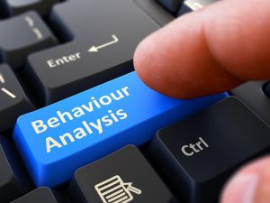 Behaviour Analysis - Written on Blue Keyboard Key. Male Hand Presses Button on Black PC Keyboard. Closeup View. Blurred Background.